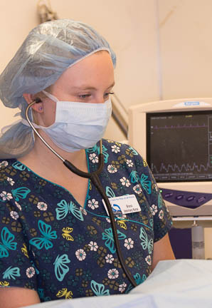 Nurse anesthetist monitoring anesthesia with a stethoscope