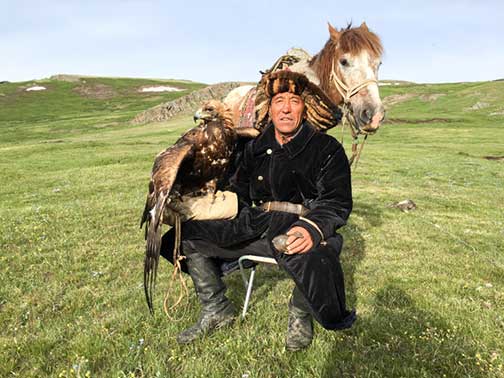 A proud Kazakh nomad with his horse and golden eagle posing for us