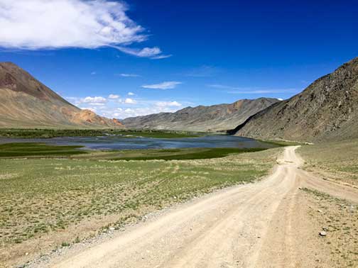 Summertime on a dusty dirt road in the mountains of western Mongolia along a river