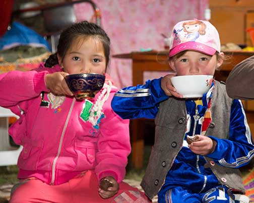 Nomad children drinking milk and tea prior to the mutton feast